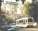 shows light rail vehicle with apartment building in the back